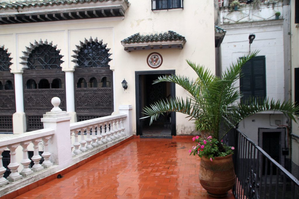 Exterior view of the American Legation Museum in Tangier, showcasing its historic architecture with whitewashed walls and intricate Moroccan tilework. Lush gardens surround the museum, highlighting its significance as a cultural and historical landmark representing the long-standing relations between the United States and Morocco.