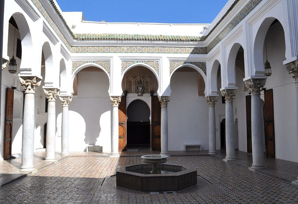 Exterior view of the Kasbah Museum in Tangier, showcasing traditional Moroccan architecture with intricate tile work and a vibrant blue door. Surrounding the museum are lush gardens and panoramic views of the city and the Mediterranean Sea, reflecting the rich cultural heritage of the region.