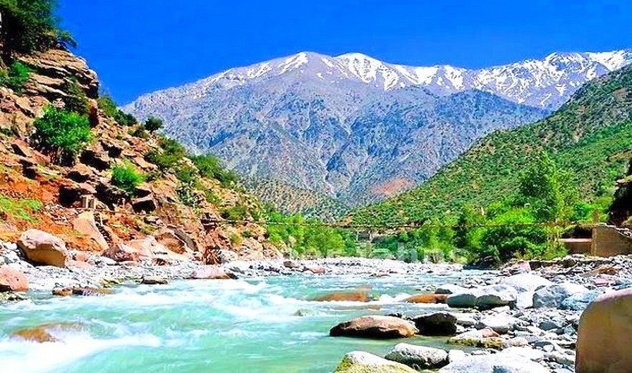 A panoramic view of Imlil, a picturesque mountain village in the Atlas Mountains of Morocco, surrounded by lush greenery and snow-capped peaks.
