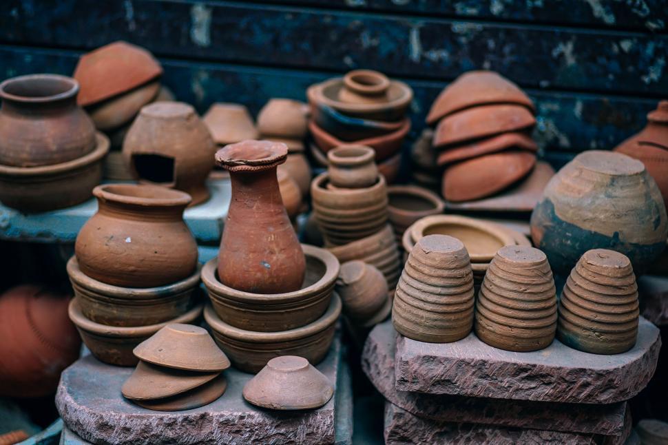 Artisan shaping traditional Moroccan tajines and various clay tools, surrounded by pottery and crafting tools in a workshop. The image showcases the intricate details and craftsmanship involved in creating these iconic Moroccan cooking vessels