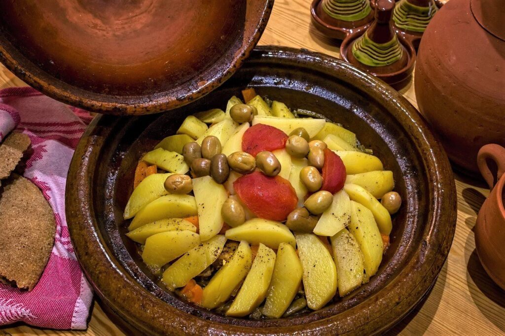 Moroccan Cuisine Tajine, A colorful Moroccan tajine dish featuring tender meat, vibrant vegetables, and aromatic spices, served in a traditional conical clay pot, showcasing the rich culinary heritage of Morocco.